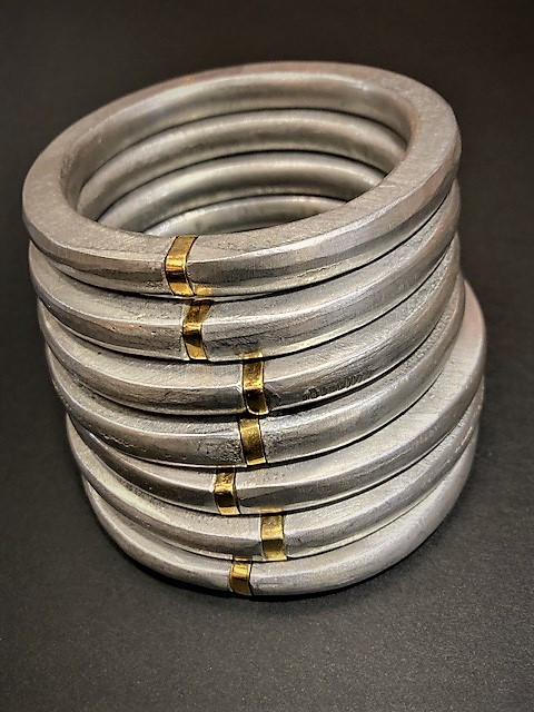 Sette bracciali in alluminio e oro